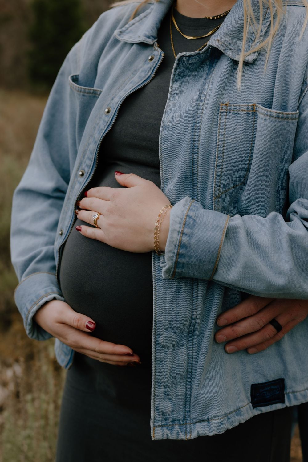 Close-up shots of a pregnant belly being cradled while wearing a denim jacket and black dress.