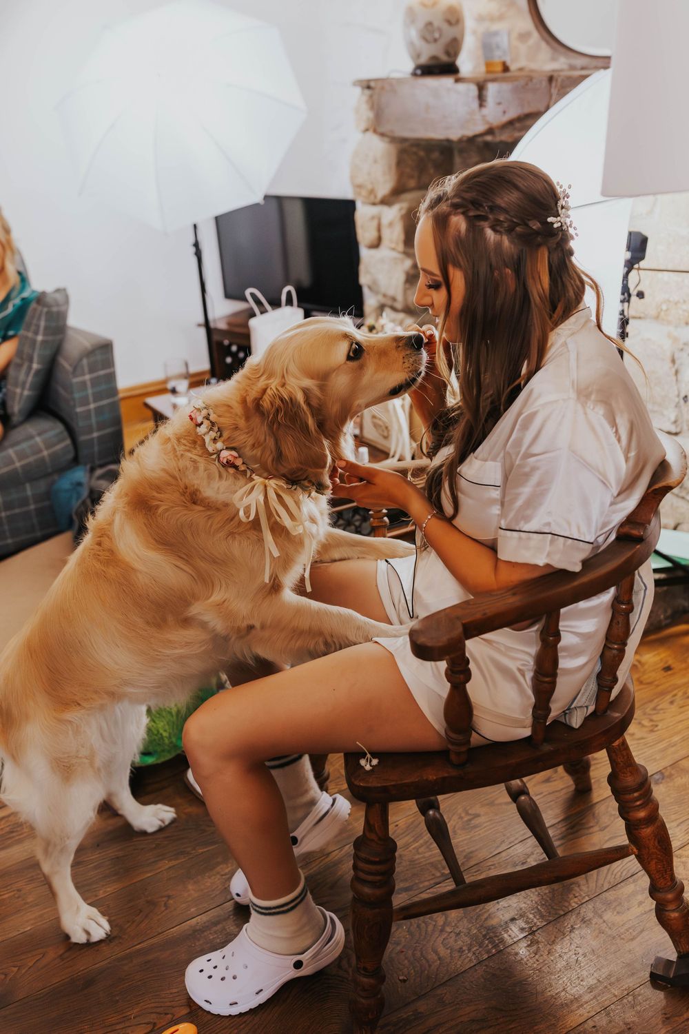 A golden retriever dog playfully interacts with someone sitting in a wooden rocking chair.