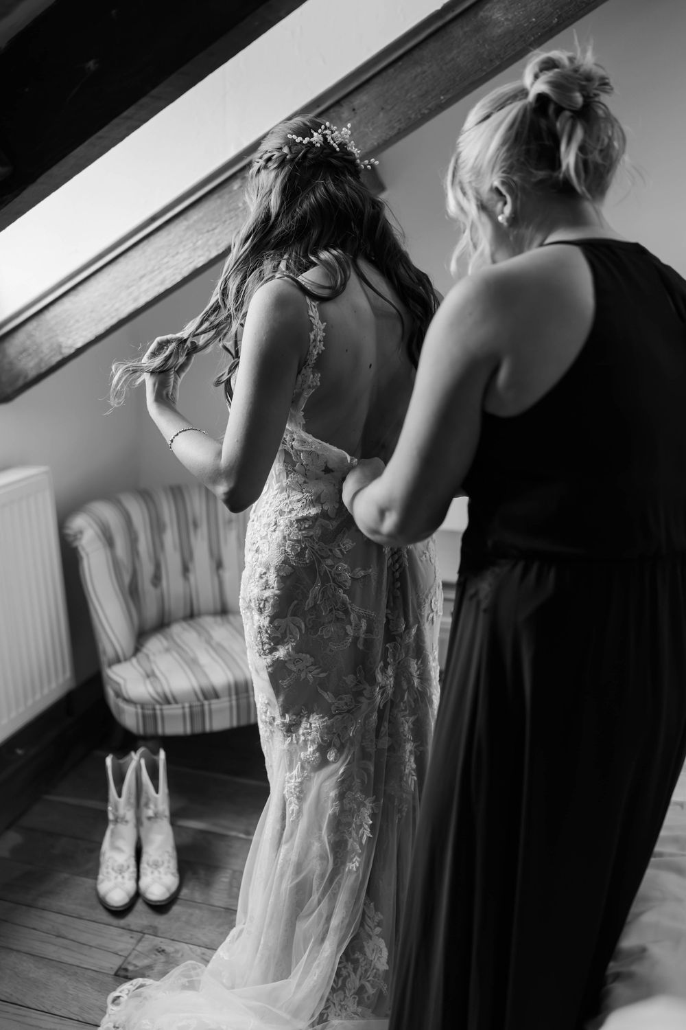 Black and white wedding preparation photos showing final dress adjustments and details before the ceremony.