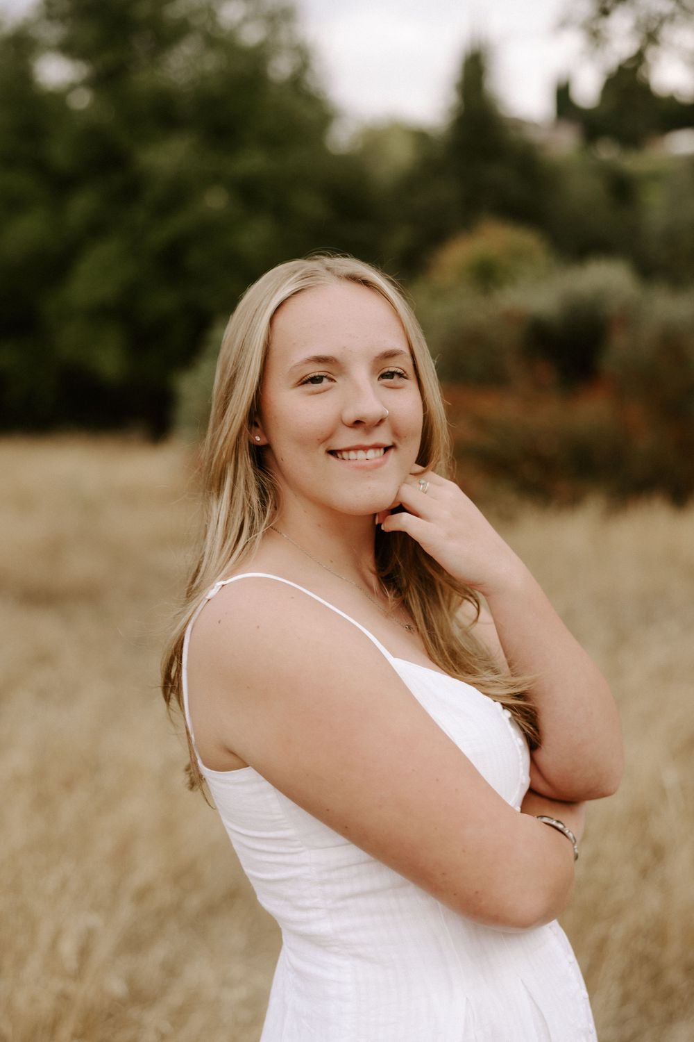 Outdoor portrait session in a rustic field with natural lighting and dried grass.