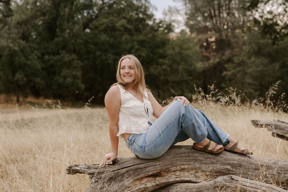 Natural light portraits taken in a rustic outdoor setting with dried grass and fallen logs.