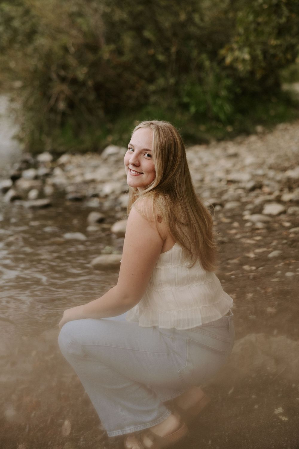 Dreamy riverside portraits captured at golden hour with stones and flowing water in the background.