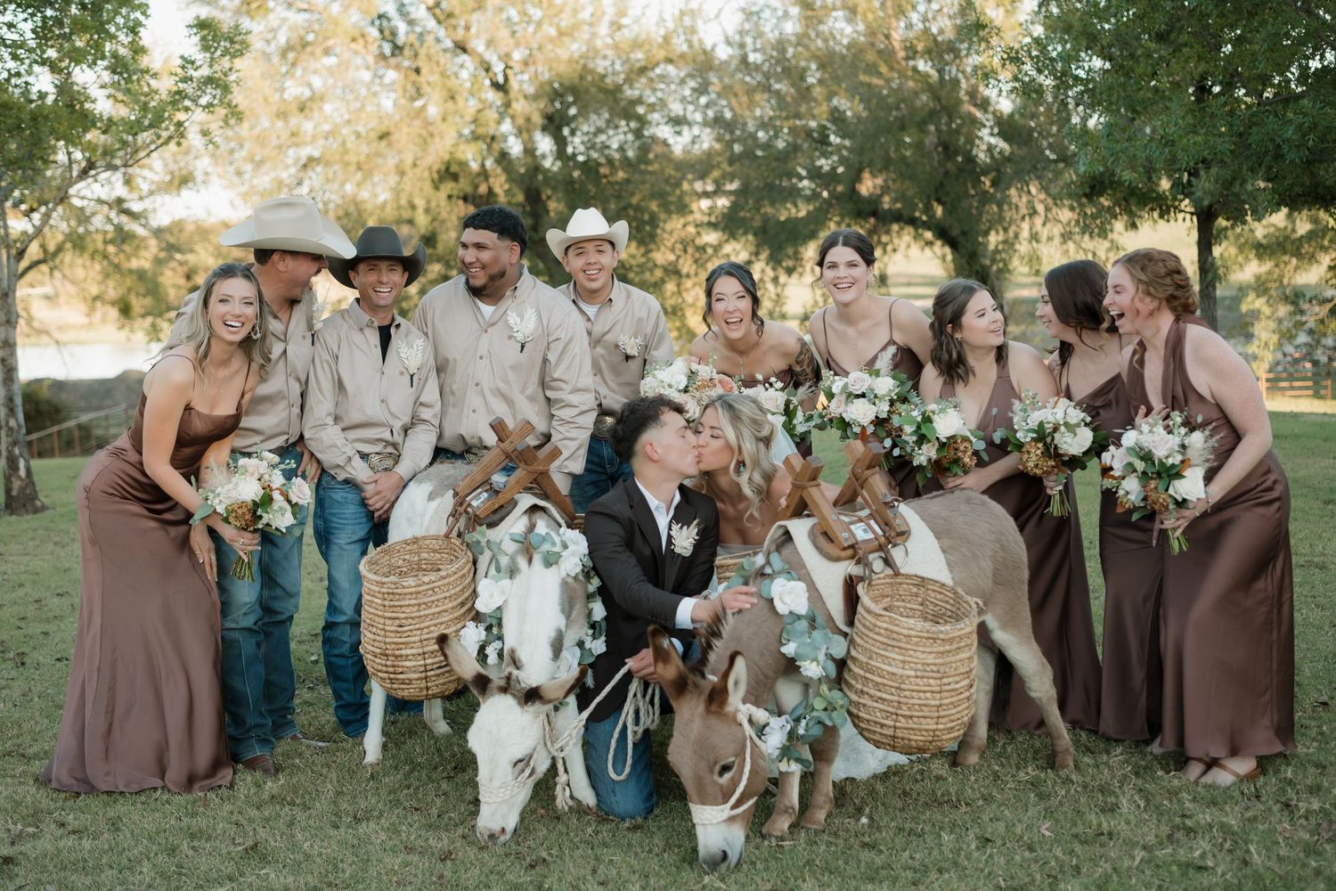 Wedding party poses together outdoors in earth tone attire during sunset in a natural garden setting.