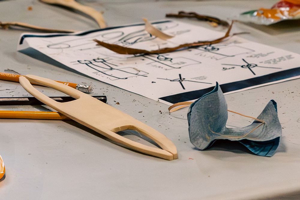 Close-up view of scattered papers, wooden hangers, and art supplies on a messy surface.