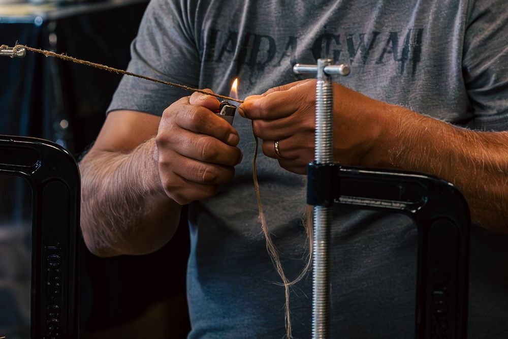 Close-up shot of hands tying fishing line around a metal pole outdoors.