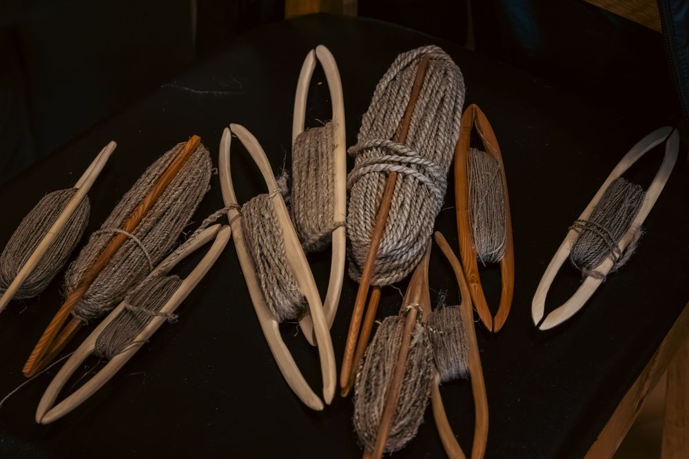 Collection of handcrafted wooden snowshoes with traditional woven webbing displayed on a dark surface.