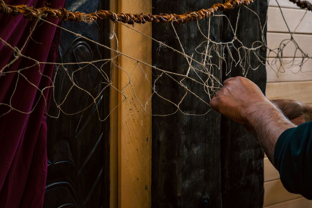 A string of orange Christmas lights hangs along a wooden beam in a dimly lit room.