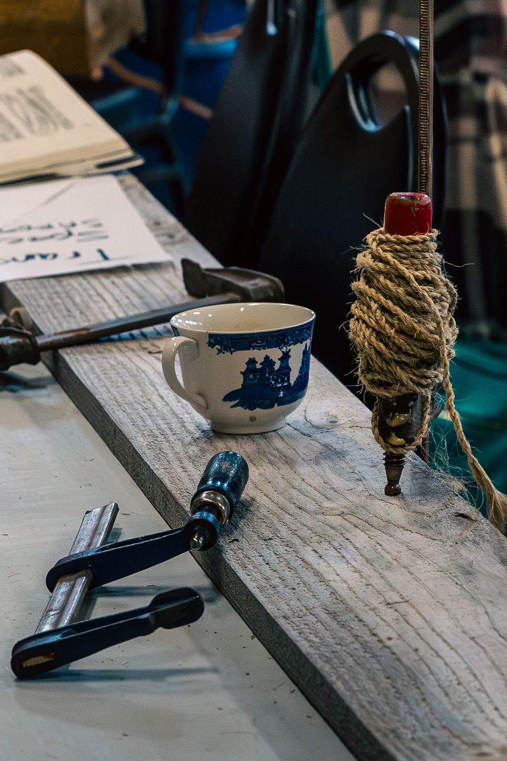 Vintage writing desk with rope-wrapped candlestick holders, teacup, and handwritten papers arranged in a moody setting.