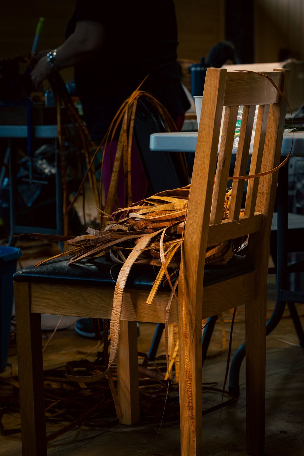 Wooden chair in dramatic lighting casts long shadows across a dark room with scattered debris visible.
