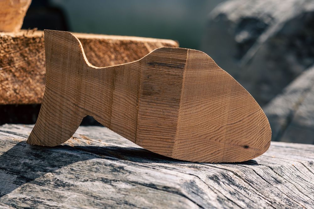 Close-up view of wooden shoe lasts used in traditional shoemaking displayed on a textured surface.