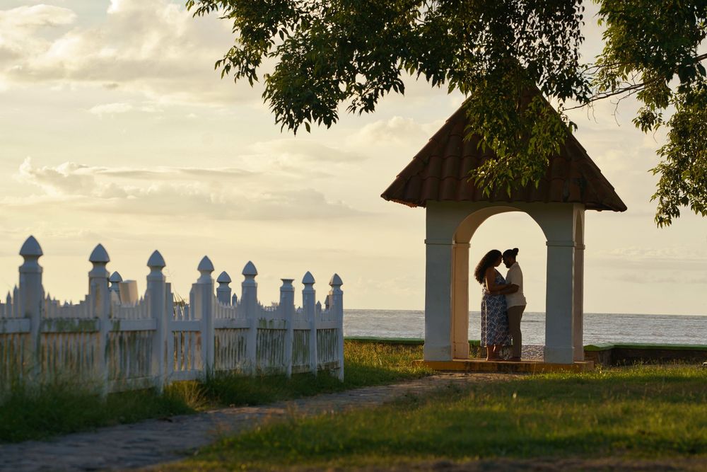 A panoramic view of silhouetted headstones and monuments in a cemetery at dusk with trees framing the horizon.