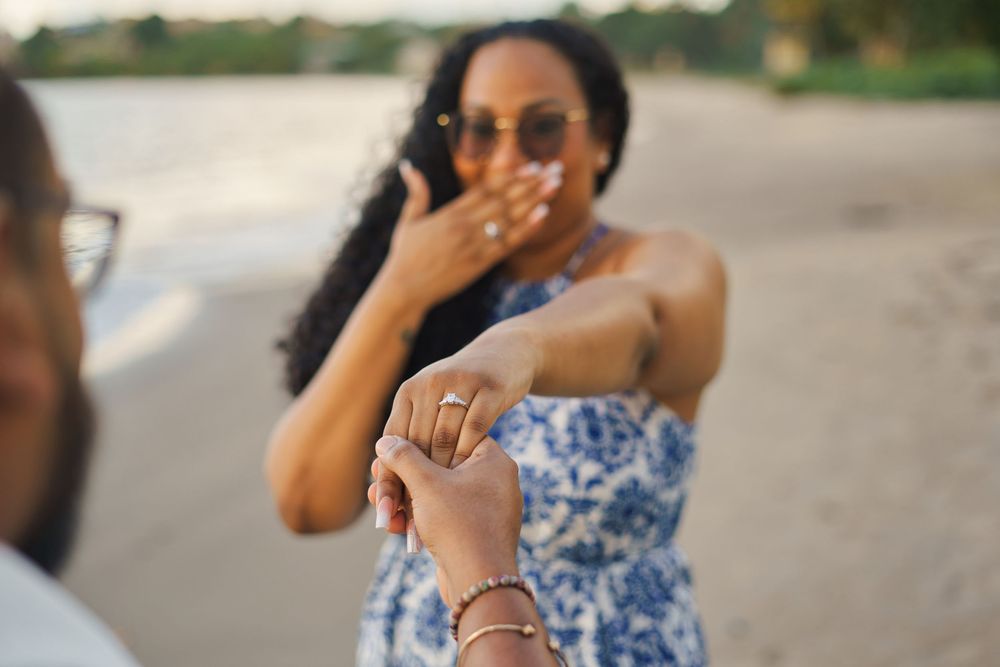 A surprised reaction to a proposal on the beach, with a close-up of an engagement ring being presented.