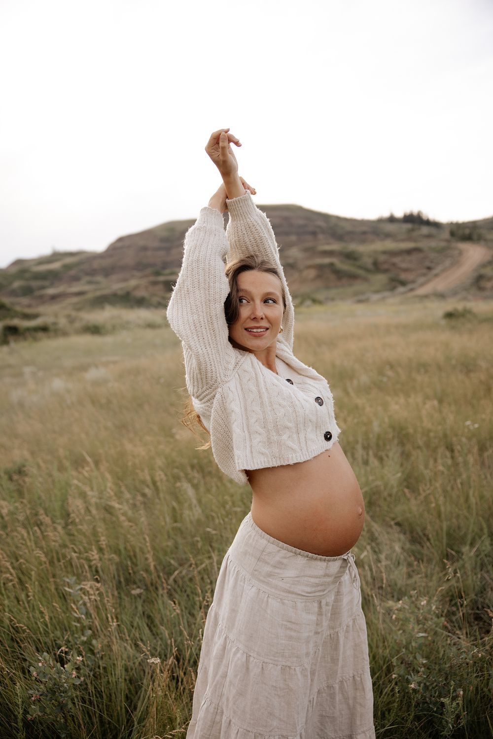 A pregnant woman in a dress poses for a maternity photographer in calgary alberta