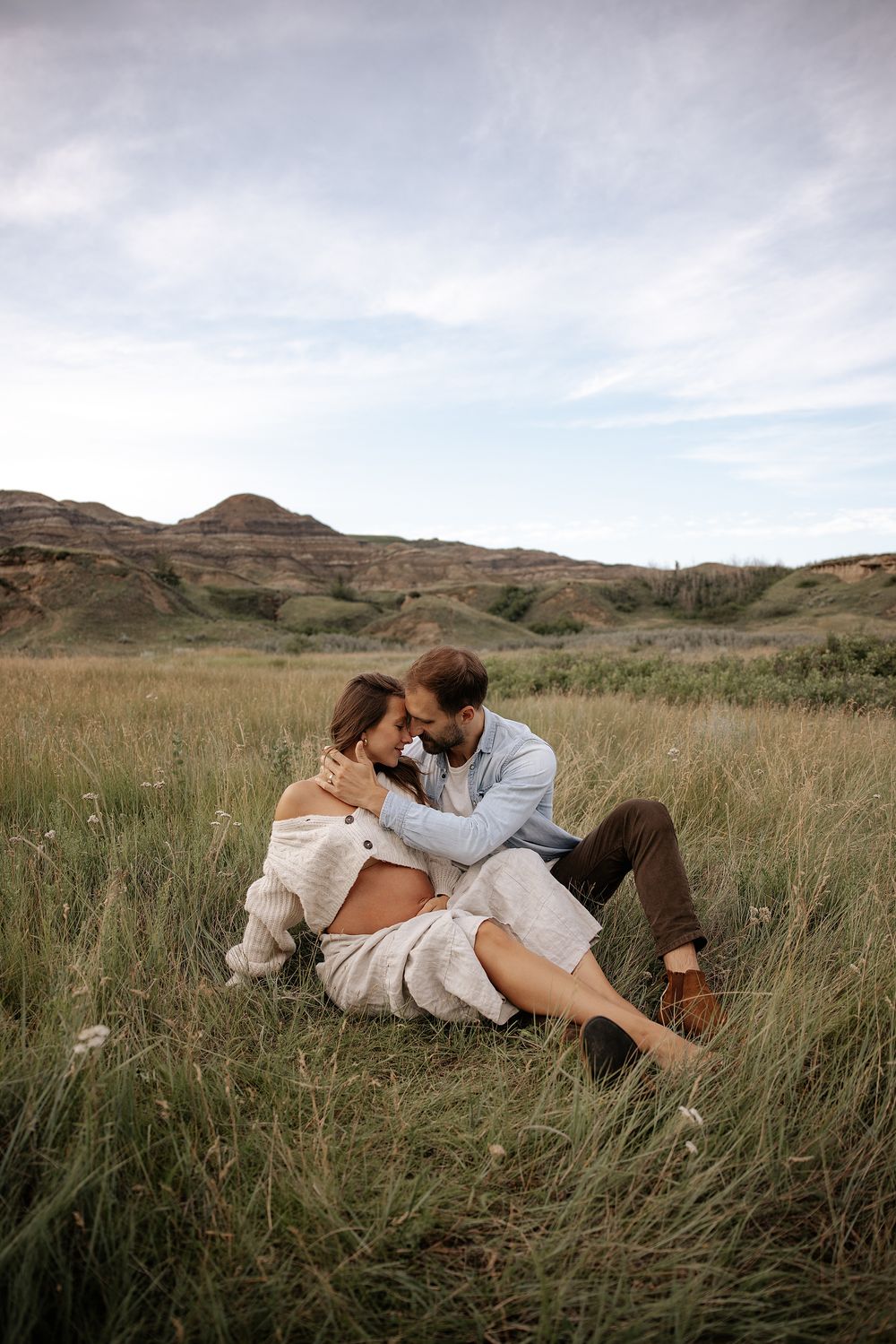 A romantic couple embraces while lying in tall prairie grass in red deer alberta