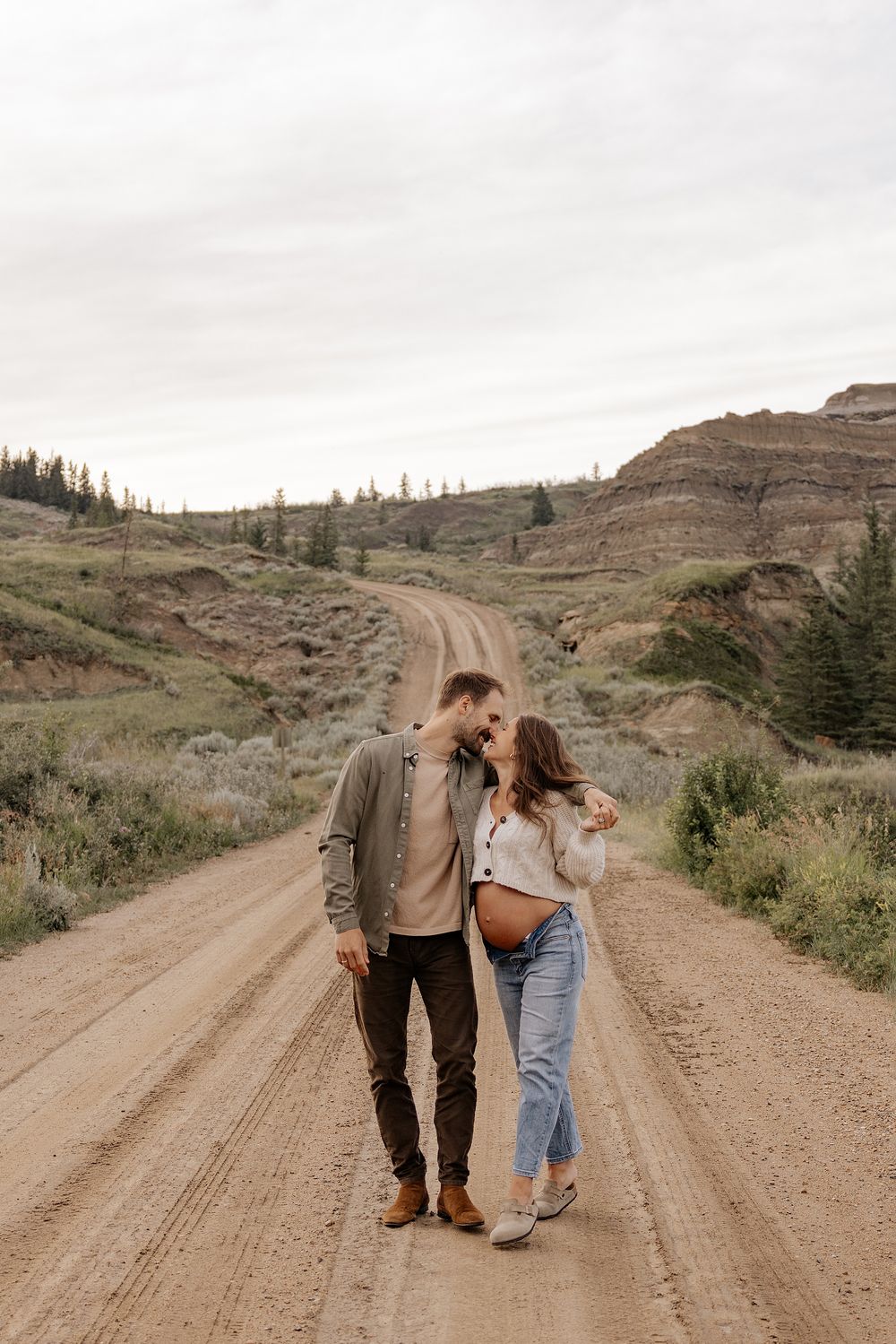 A couple walks intimately together being photographed for their maternity session in red deer alberta