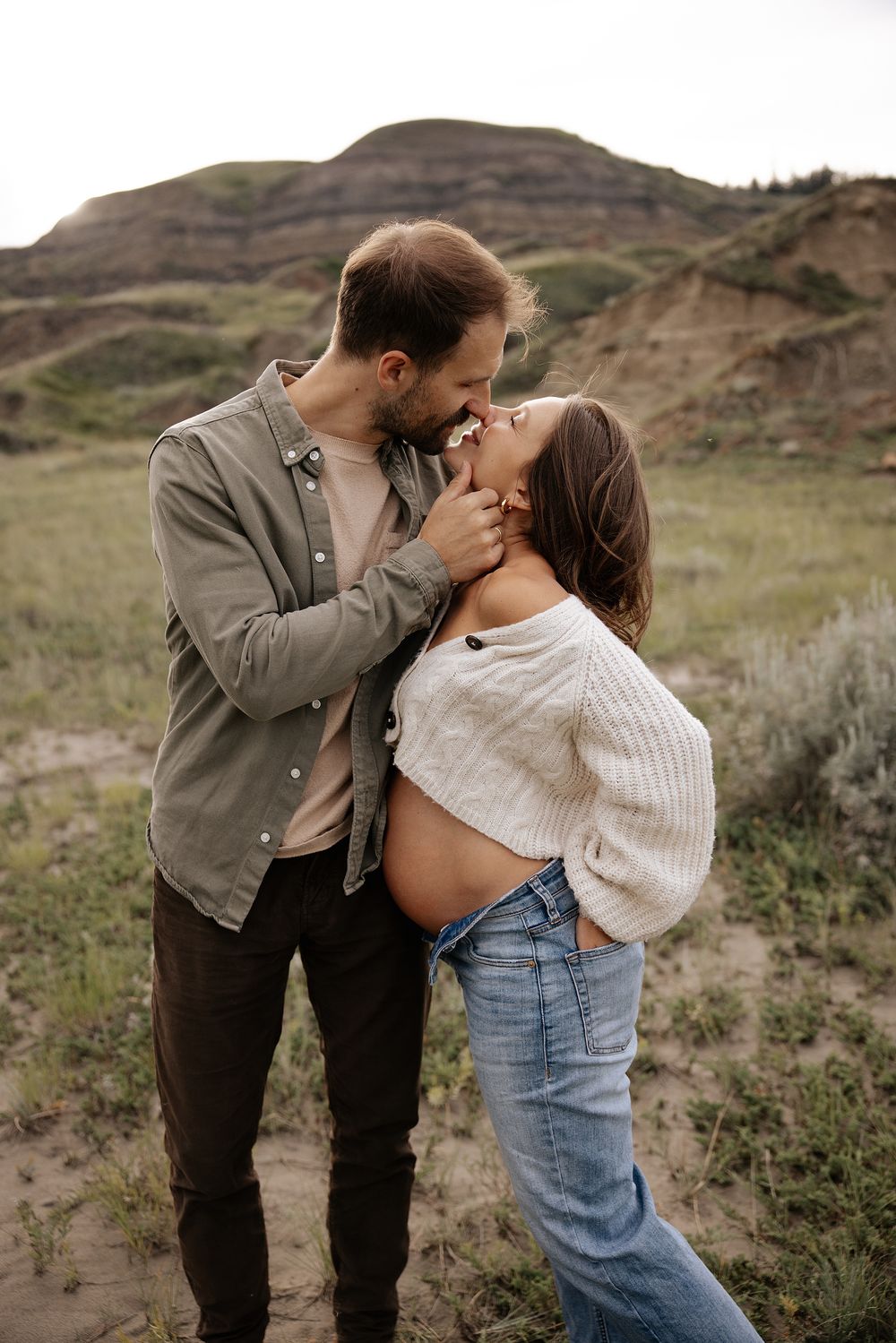 Romantic couple embraces in a scenic mountain landscape during golden hour.