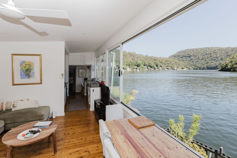 Modern lakefront home interior with wood floors and large windows offering panoramic water views.