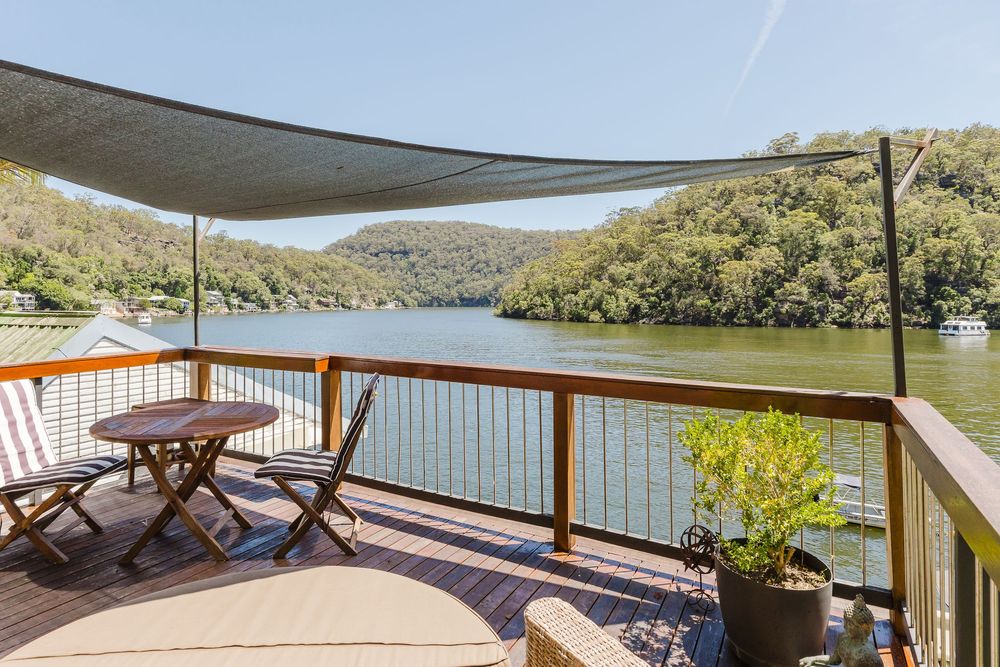 A panoramic view of a wooden deck overlooking a serene lake surrounded by lush green mountains.