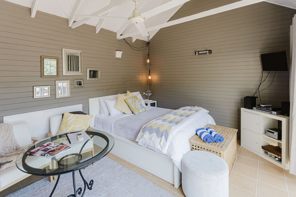 Cozy coastal-style bedroom with white bedding, exposed beams, and natural wood accents creates a serene atmosphere.