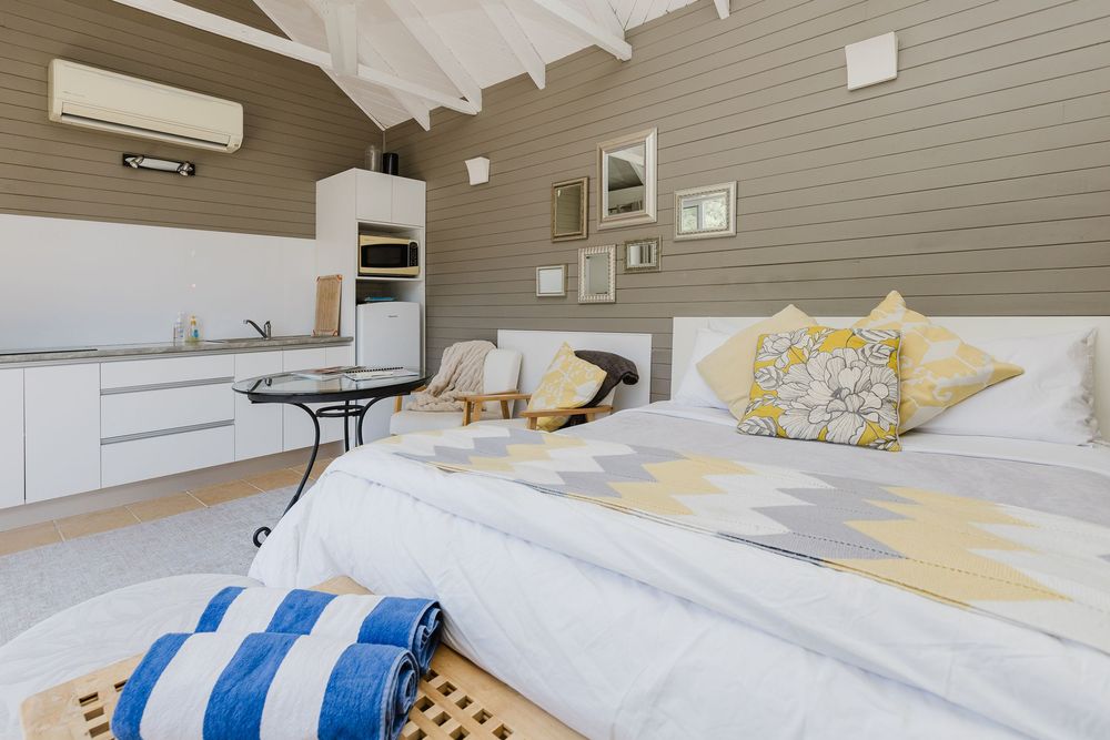 Bright and airy coastal bedroom with white bedding, blue striped pillows, and natural wood accents.