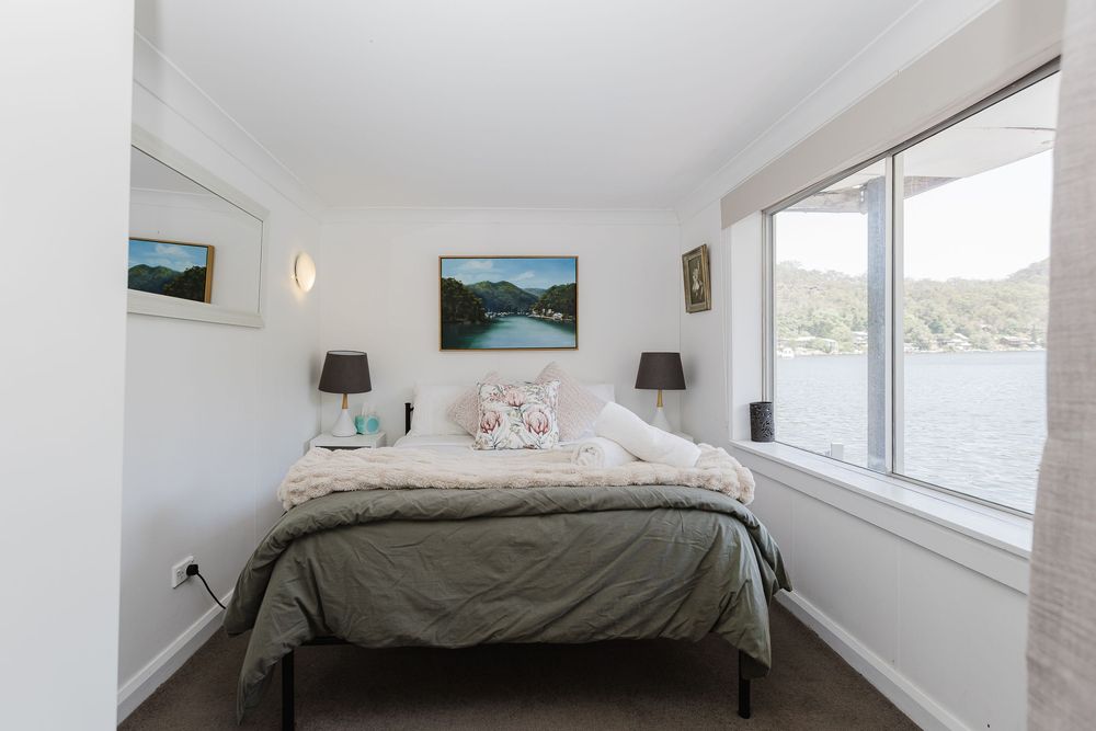 Modern bedroom with white walls, sloped ceiling, and large windows offering mountain views and natural light.