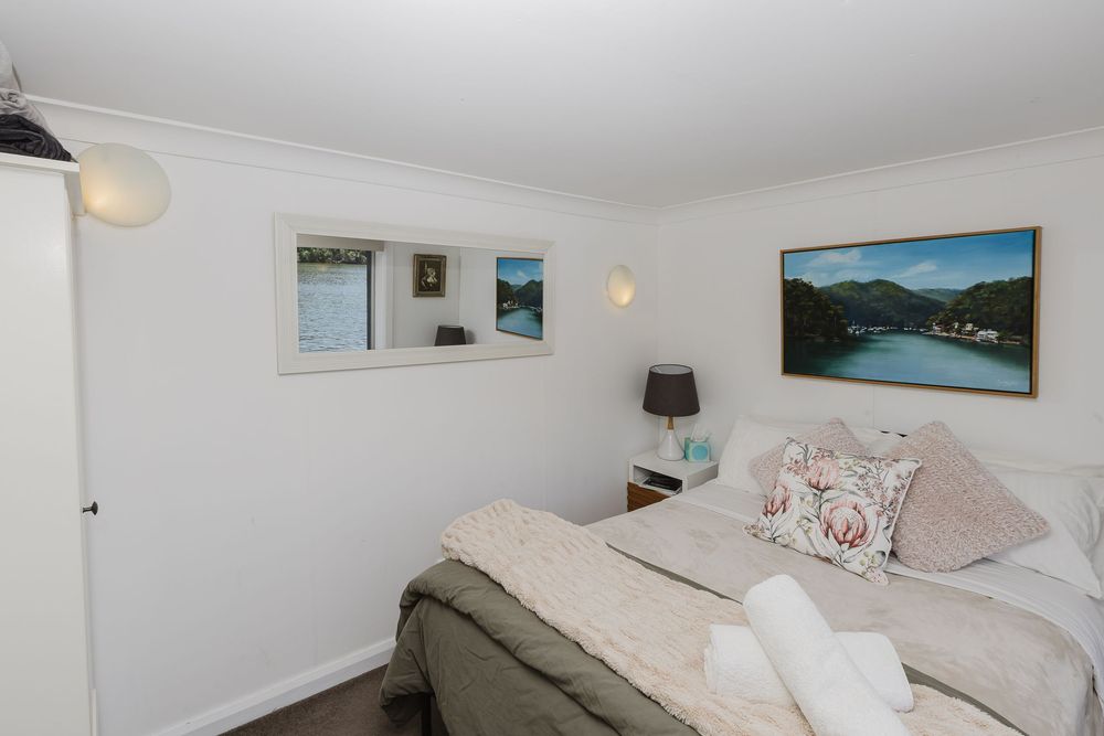 Bright white bedroom with coastal decor features mounted artwork, plush bedding, and natural lighting.