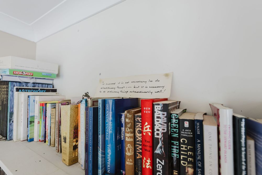 A collection of books arranged on white shelves against a white wall showing various colored spines and titles.