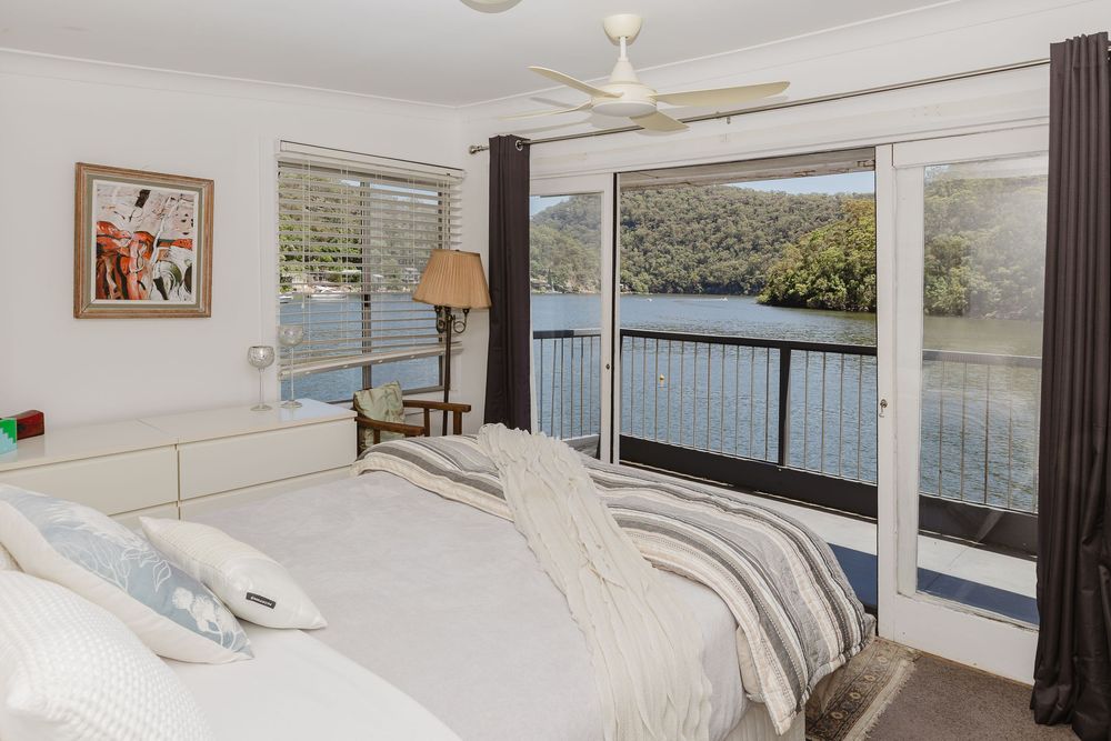 Bright and airy modern bedroom with white bedding, wood accents, and natural light streaming through large windows.