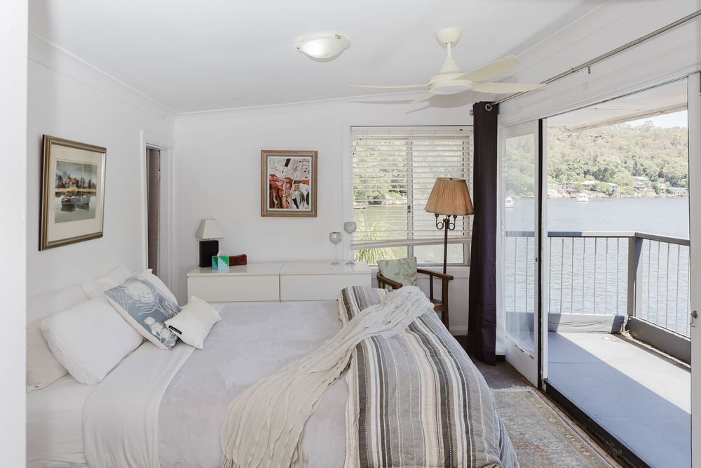 Modern white bedroom interior with large windows, recessed lighting, and minimal contemporary furnishings.