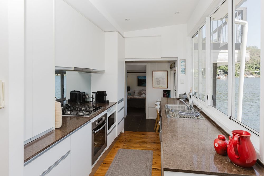 Modern white interior hallway with hardwood floors and natural light streaming through large windows.