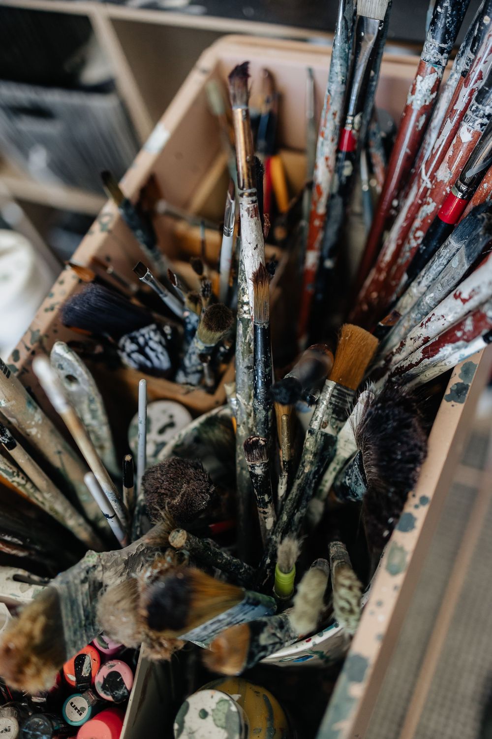 Close-up of used paint brushes with dried paint residue standing upright in a holder.