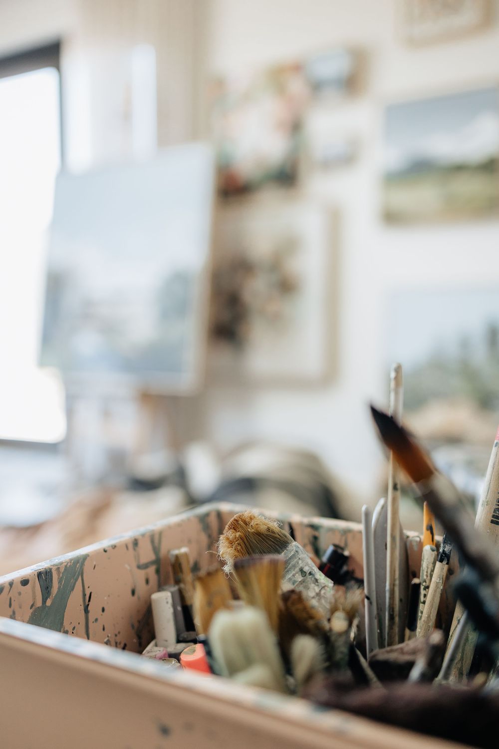 Close-up view of art supplies and brushes organized in storage containers on a desk.