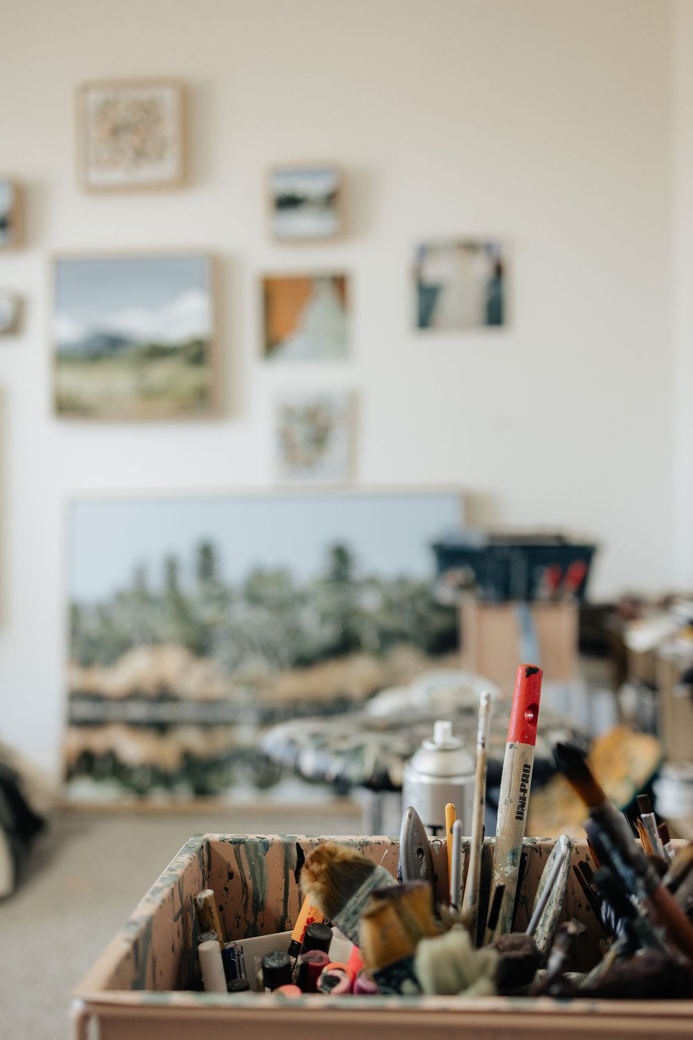 Art supplies and paintbrushes arranged in wooden holders on a studio workspace.
