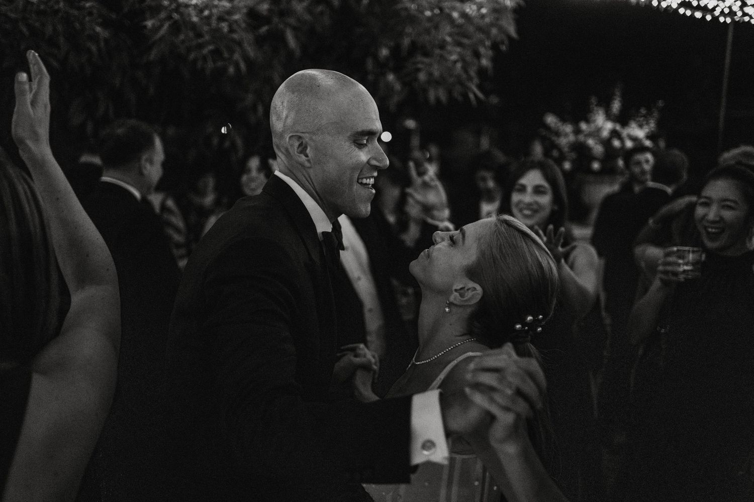 Wedding guests laughing and celebrating during outdoor reception.