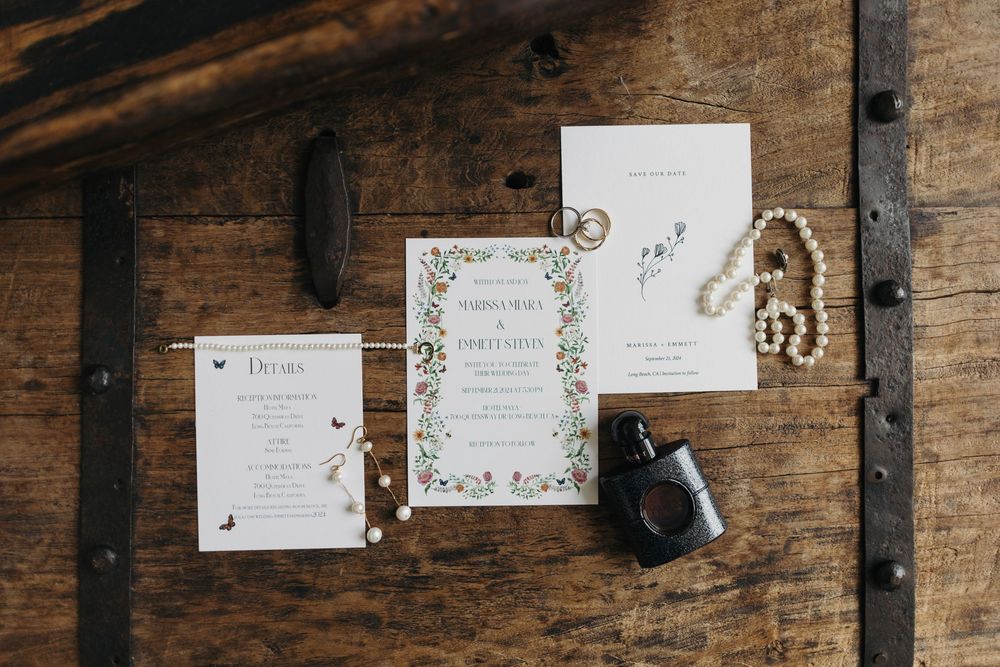 Rustic wooden table displaying elegant wedding invitation suite with floral designs.