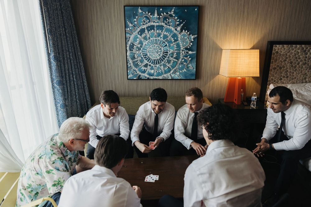 Group playing cards around a table with decorative mandala art on the wall and warm lighting.