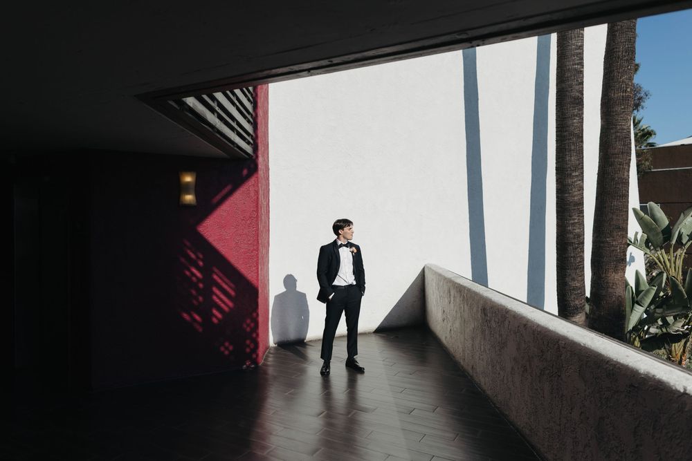 Silhouette of person in formal wear standing in modern architectural corridor with dramatic lighting.