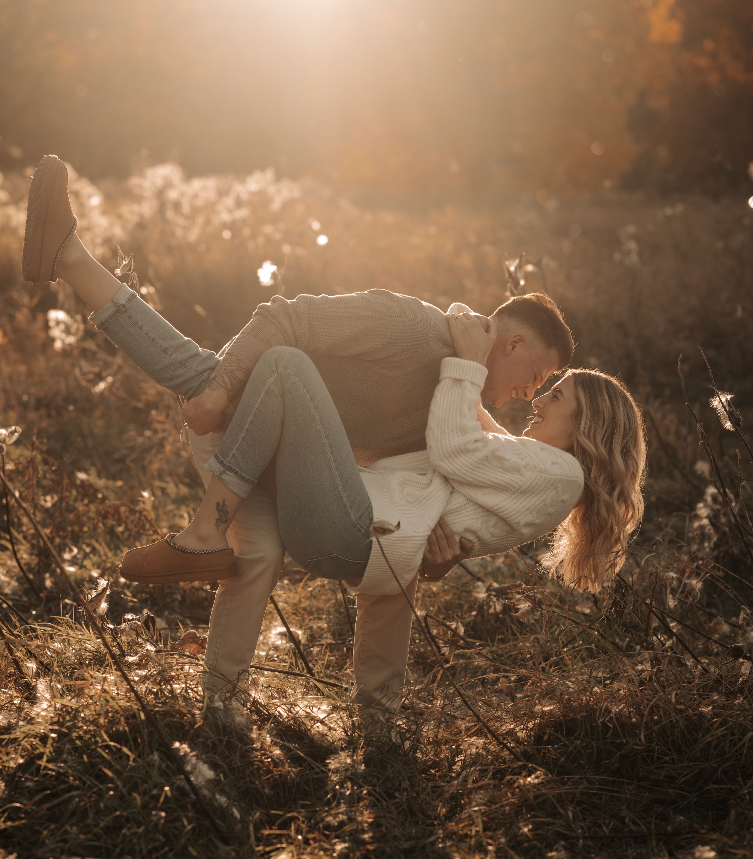 Romantic couple embracing in golden sunlight amongst autumn foliage during a dreamy outdoor photoshoot.