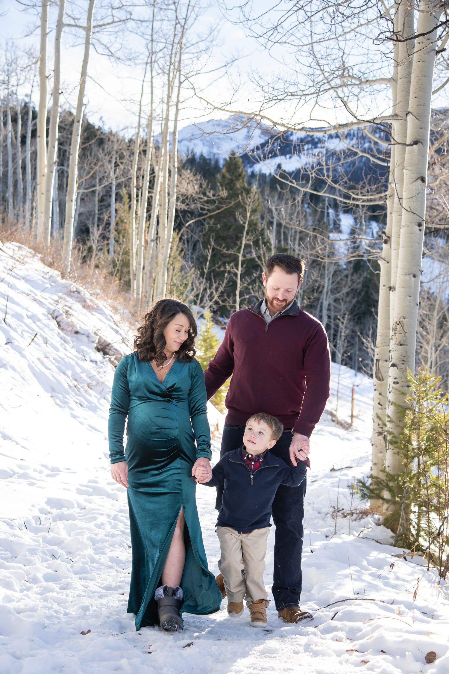 Cute family photo session during the winter with snow and aspen trees around them with snowy mountains in the background in Aspen Colorado