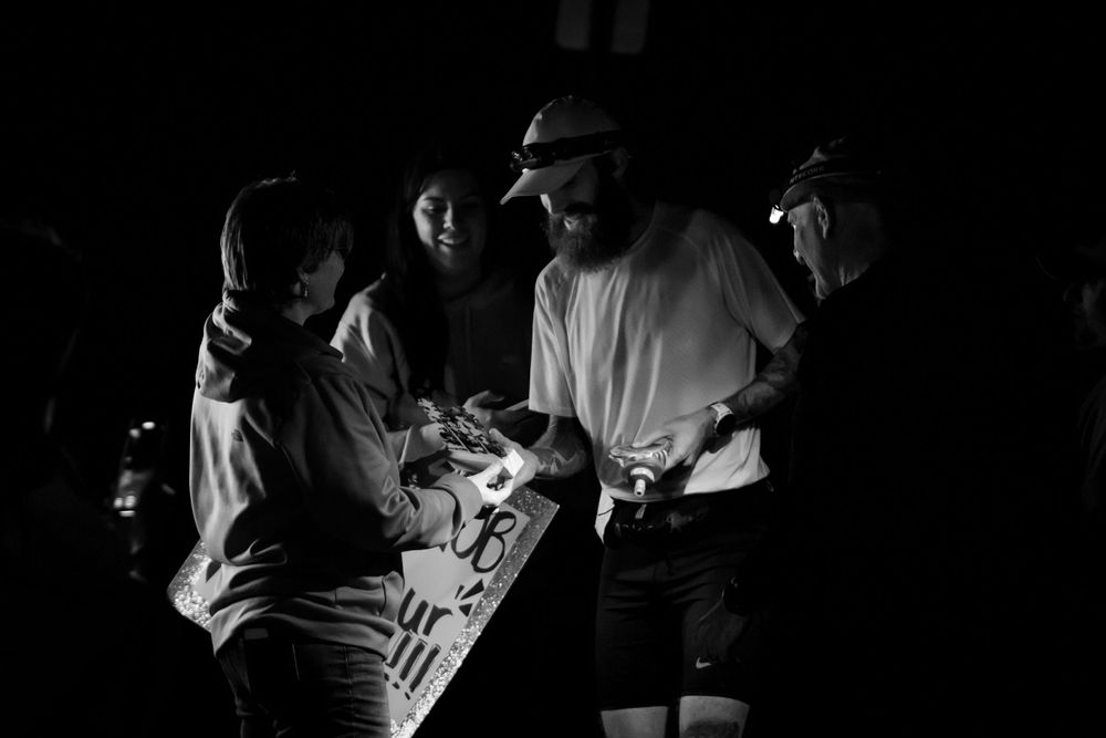 Black and white nighttime shot of runners at race checkpoint.