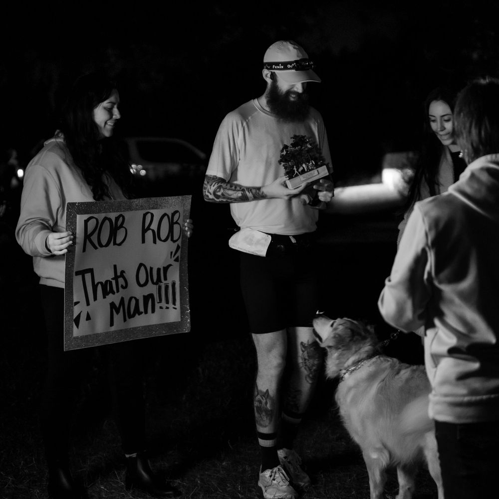 A nighttime gathering showing supporters holding a sign at an outdoor event.