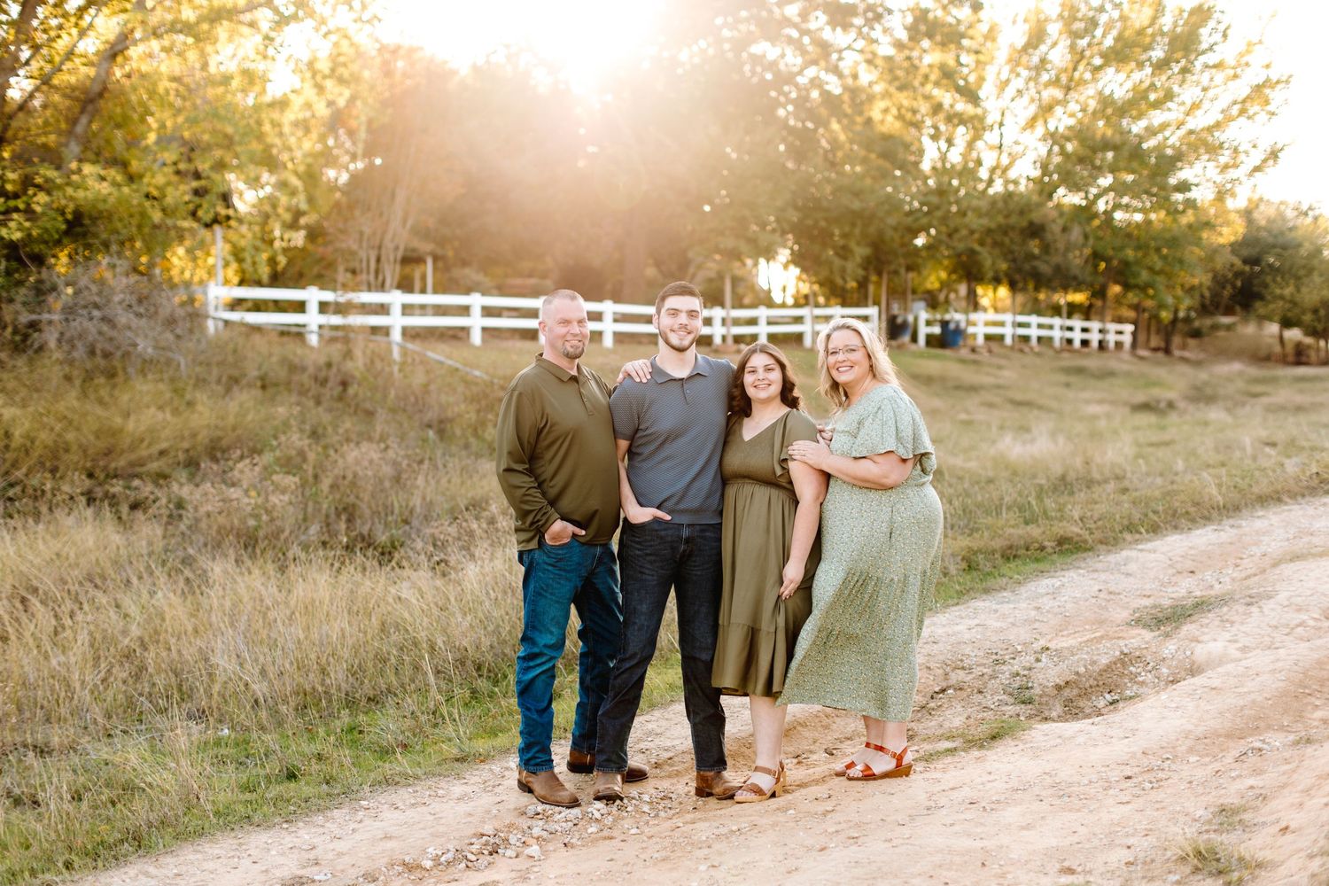 Beautiful sunset family photo session in a rustic outdoor setting with white fences.