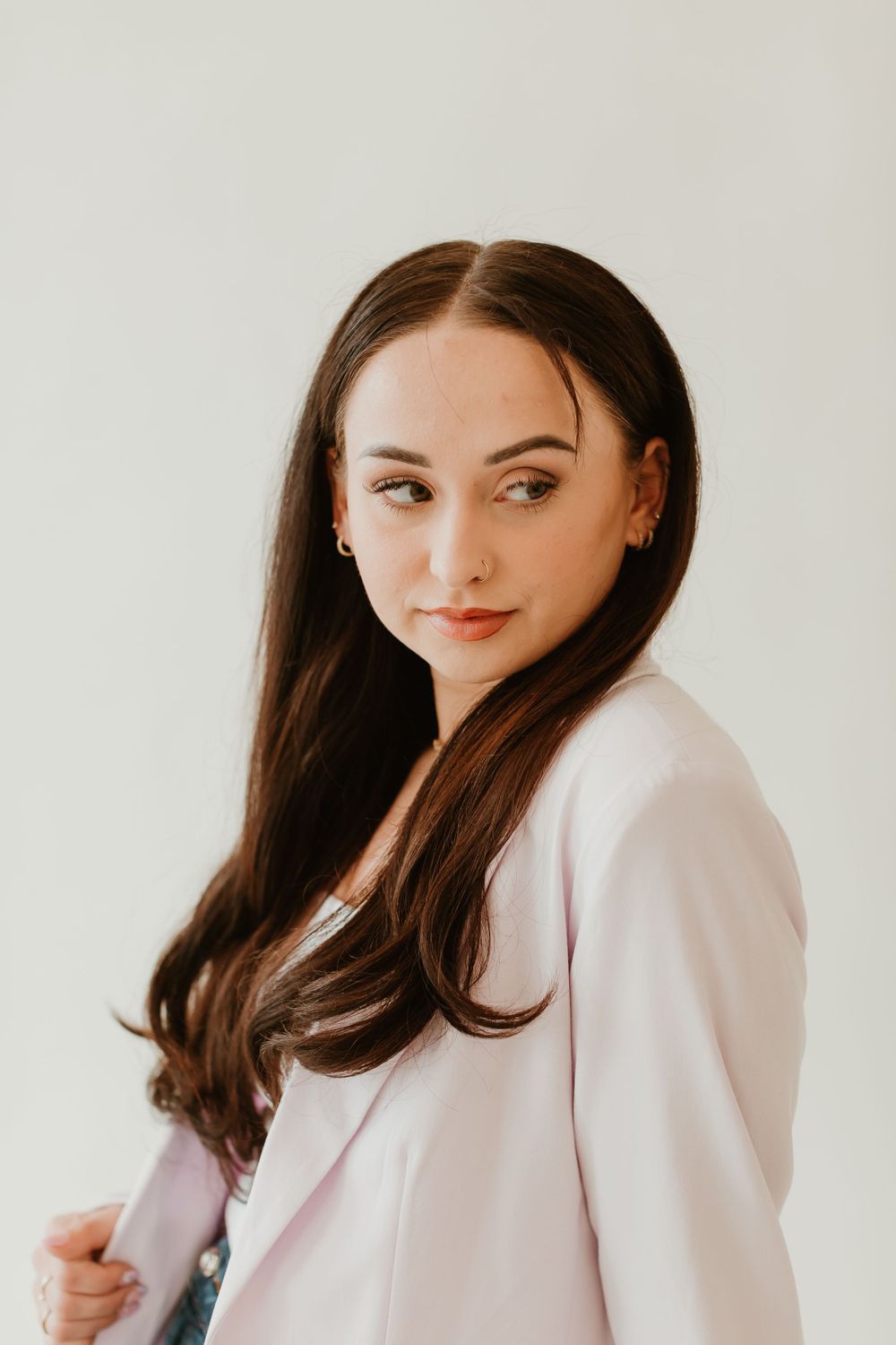 Professional portrait in a light pink blazer against a neutral background.