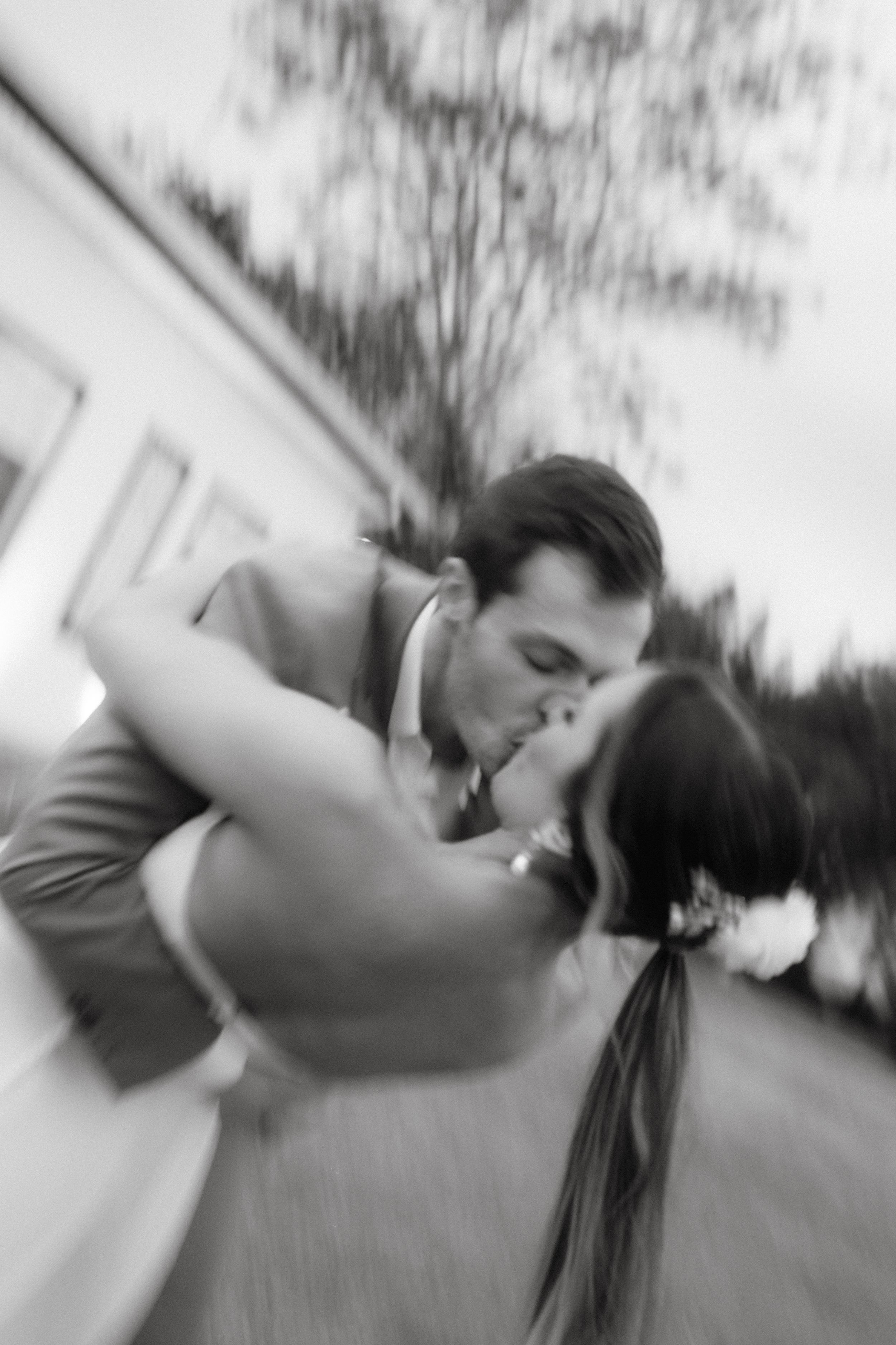 A black and white motion blur photo of a romantic dance dip during a wedding.