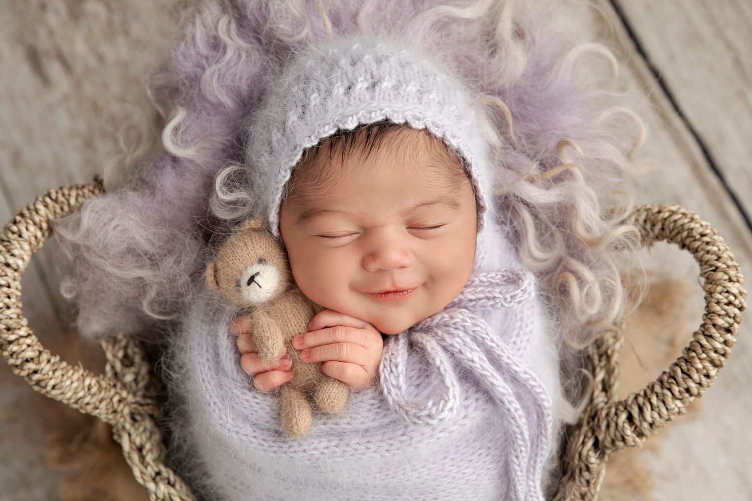 Sleeping baby in white bonnet with plush toy in woven basket.