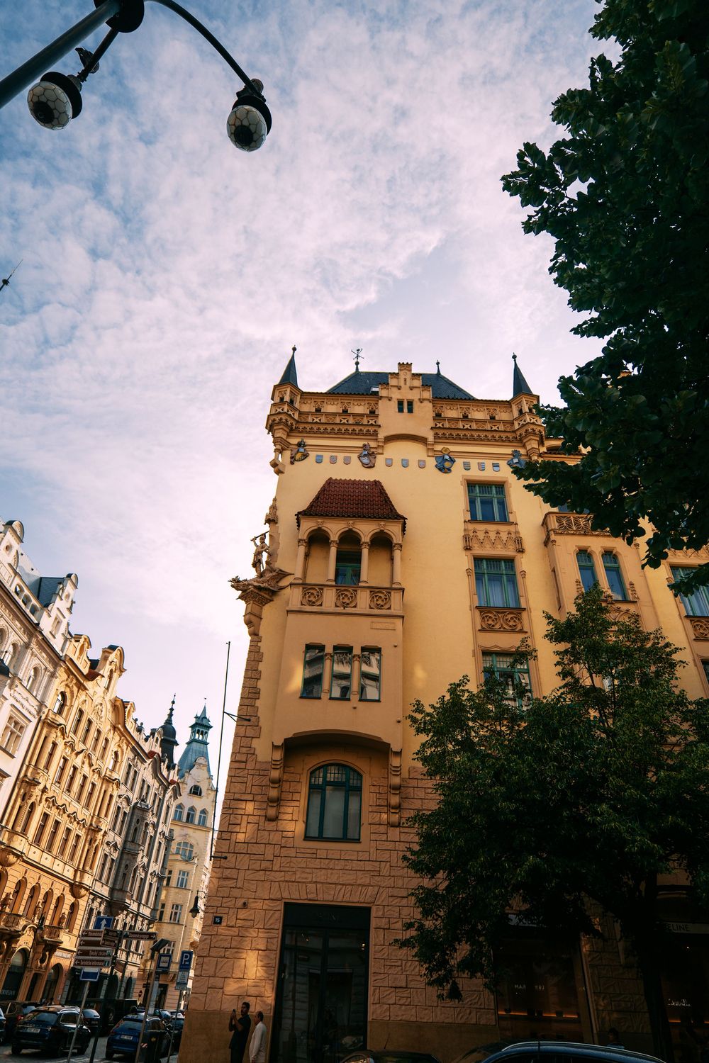 Historic Gothic-style building with yellow facade and ornate architectural details along a European city street.