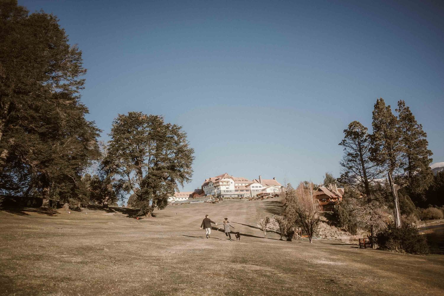 Pareja recién comprometida abrazándose frente al paisaje alpino del Hotel Llao Llao en la Patagonia argentina