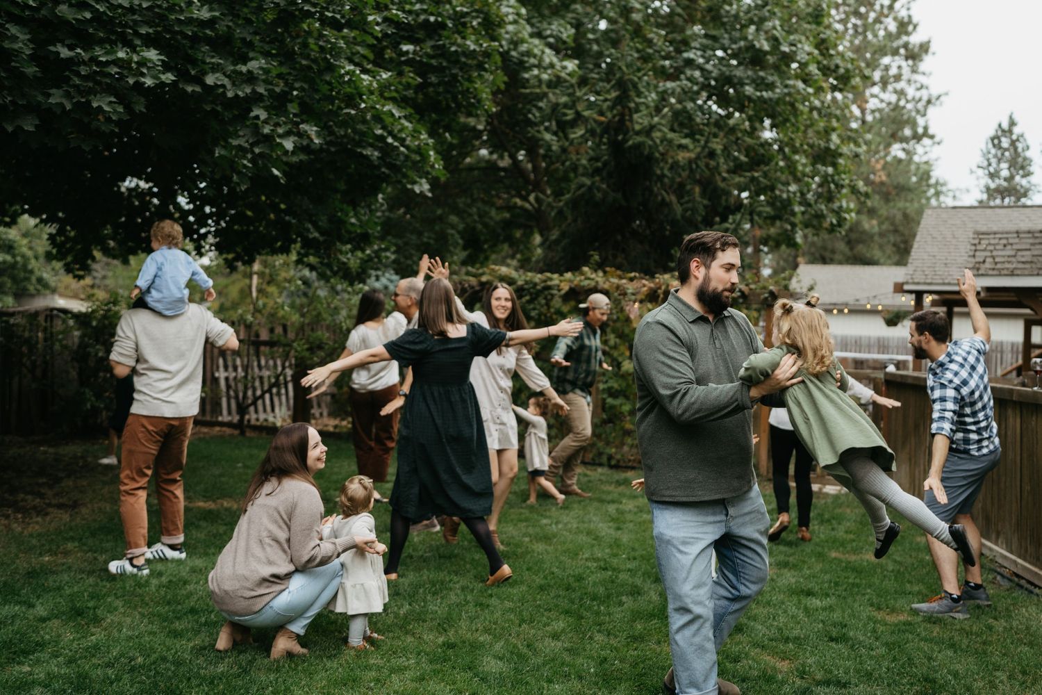 Wedding guests dancing and celebrating on backyard lawn.