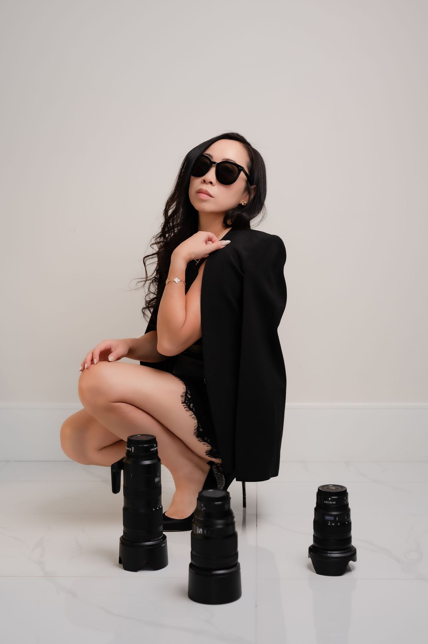 Photographer using professional camera lens while wearing cozy cream sweater for self portrait in soft lighting.