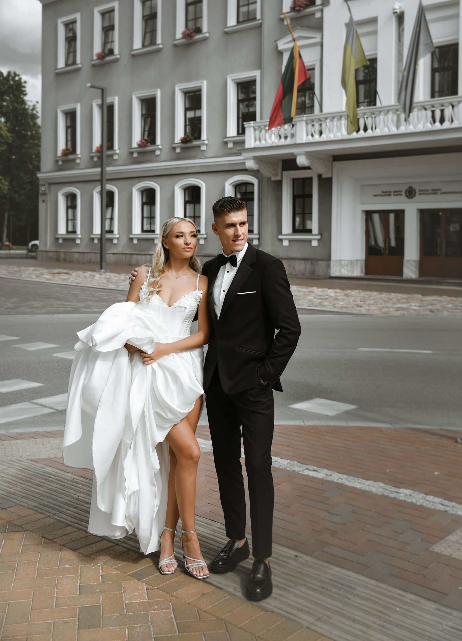 Stylish wedding couple posing in front of classic European building facade.